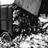 Historische Aufnahme eines Müllwagens beim Müll abladen